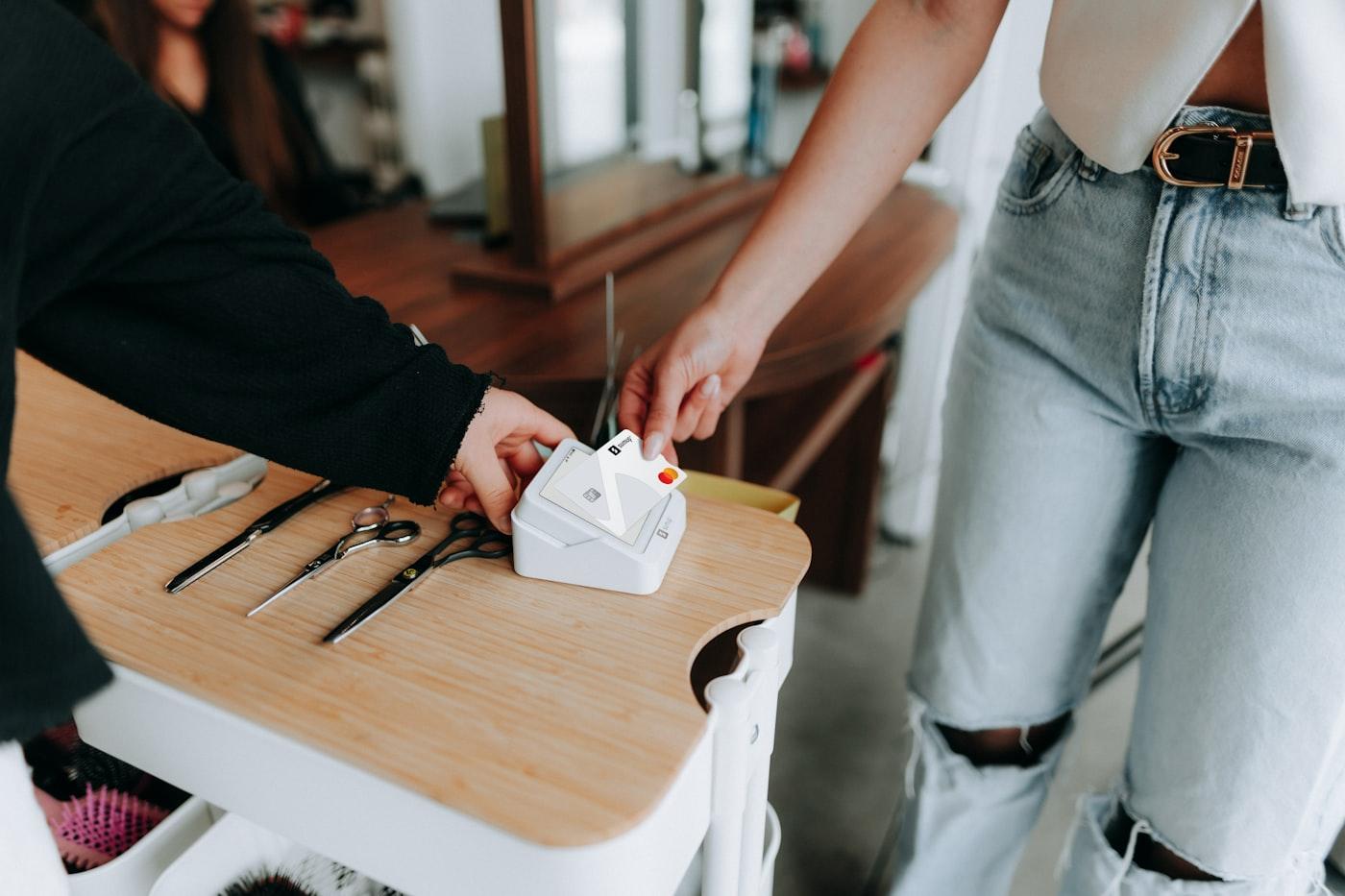 A customer tapping a card on a handheld reader at a counter