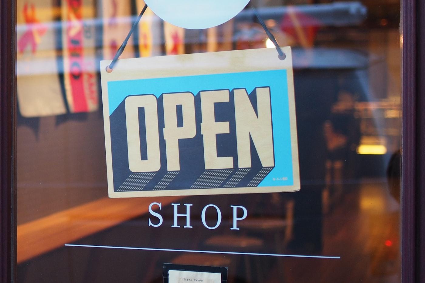 A hand-painted OPEN sign hanging in a shop door on opening day